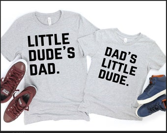 May include: Two gray t-shirts with black text that reads "LITTLE DUDE'S DAD" and "DAD'S LITTLE DUDE." The shirts are paired with maroon and blue sneakers. The image text says "MATCHING FATHER AND SON" and "DIGITAL DOWNLOAD."