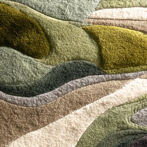May include: A textured rug with a layered design in shades of green, brown, and cream. The rug's pattern resembles rolling hills or abstract landscape, with varying textures and depths. The rug has a soft, plush appearance.