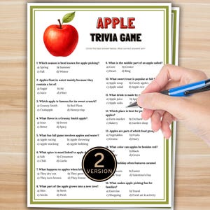 May include: A printed trivia game sheet titled "APPLE TRIVIA GAME" with multiple-choice questions about apples. A large red apple graphic is at the top. A hand holding a blue pen is visible, ready to answer the questions.
