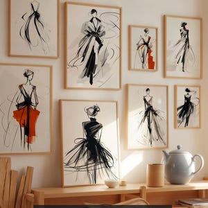 Op de afbeelding: Een verzameling ingelijste modeschetsen in zwart-wit, met accenten van oranje en rood. De kunstwerken tonen verschillende poses en stijlen. De tekst "40 Fashion Sketches" is zichtbaar onderaan de afbeelding.