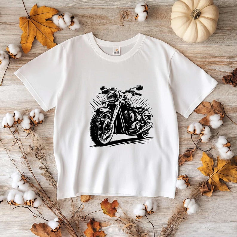 May include: White t-shirt with a black and white illustration of a motorcycle. The motorcycle has a large front wheel and a smaller back wheel.