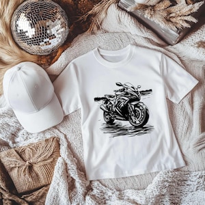 May include: White t-shirt with a black and white illustration of a motorcycle.