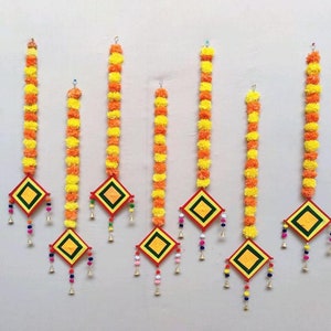 Può includere: Ghirlande decorative sospese con vivaci fiori di calendula arancioni e gialli. Ogni ghirlanda presenta un ornamento a forma di diamante con dettagli rossi, verdi e gialli, accentuato da piccole campane e perline colorate. Ideale per decorazioni festive.