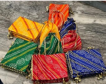 May include: A collection of colorful fabric pouches and rectangular cases. The pouches are drawstring style, and the cases are rectangular with gold trim. The fabrics feature patterns in yellow, orange, green, red, and blue.