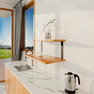 Pode incluir: Uma cozinha moderna com bancada de madeira clara e superfície com padrão de mármore branco. Duas prateleiras de madeira são montadas na parede, com um pequeno vaso de vegetação na prateleira superior e uma chávena de chá na prateleira inferior. Uma chaleira elétrica de aço inoxidável está na bancada.