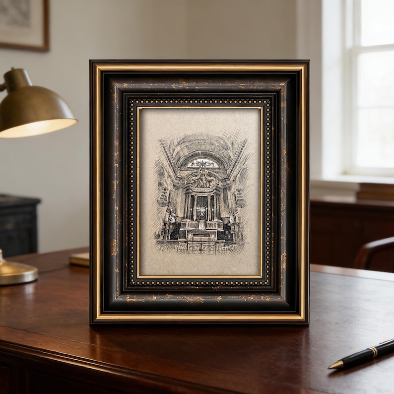 May include: A framed black and gold sketch of a church interior. The frame has a detailed, ornate design with a gold inner border. The sketch is in black and white, depicting architectural details.