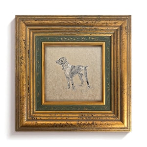 May include: A framed print featuring a black and white illustration of a dog. The frame has a gold finish with green accents. The dog is standing on grass.