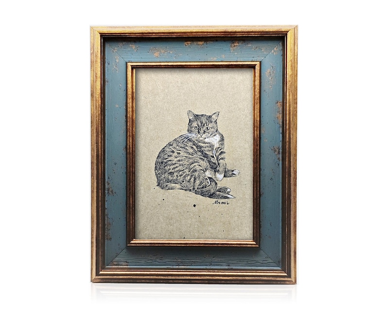 May include: A framed cat art print. The frame has a distressed blue exterior with a gold interior border. The artwork is a detailed black and white illustration of a tabby cat sitting and grooming itself.
