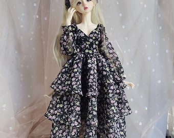 May include: A doll wearing a black and white floral dress with a tiered skirt. The doll has long blonde hair and is wearing a black headband.