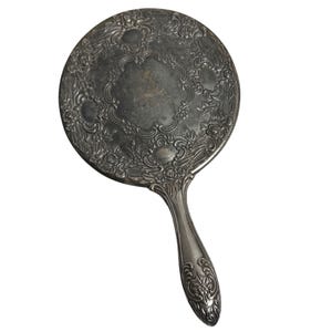 May include: A white ceramic mug with a black handle and the text "But First, Coffee" in a black, handwritten-style font. The mug is on a white surface.