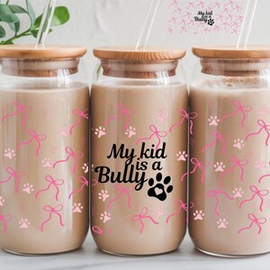 May include: Three clear glass jars with bamboo lids and pink and white paw print and bow designs. The middle jar has the text "My kid is a Bully" with a black paw print.