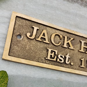 May include: A brass plaque with the text "JACK  Est. 1" in a vintage style font.