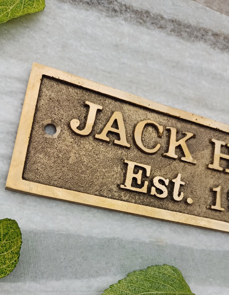 May include: A brass plaque with the text "JACK  Est. 1" in a vintage style font.