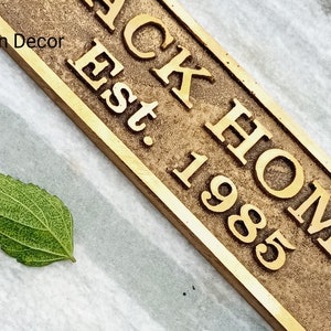 May include: A brass sign with the text "BACK HOME Est. 1985". The sign has a rustic, aged look.