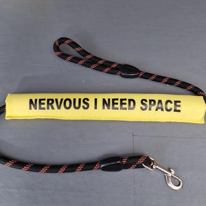May include: A black and red rope lead with a yellow padded handle that reads "NERVOUS I NEED SPACE".