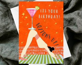 May include: A birthday greeting card with a vibrant orange background and the text "ITS YOUR BIRTHDAY! BOTTOMS UP!". The card features a pink cocktail illustration and a person in a yoga pose on a striped mat.