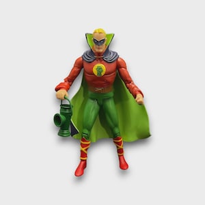 May include: A Green Lantern action figure, dressed in a red and green costume with a green cape. The figure holds a green lantern and wears a black mask. The figure is approximately 15 cm tall.