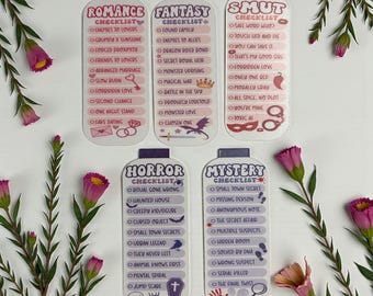 May include: Five checklist cards with different themes: Romance, Fantasy, Smut, Horror, and Mystery. Each card has a unique design and a list of related terms. The cards are white with colorful text and graphics, and are surrounded by pink flowers.