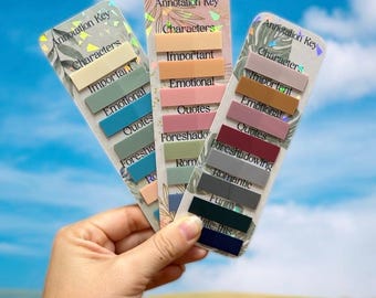 May include: Three annotation key bookmarks with colorful labels. Each bookmark has a holographic top with text that reads "Annotation Key" and labels like "Characters," "Important," and "Quotes." The background is a blue sky.