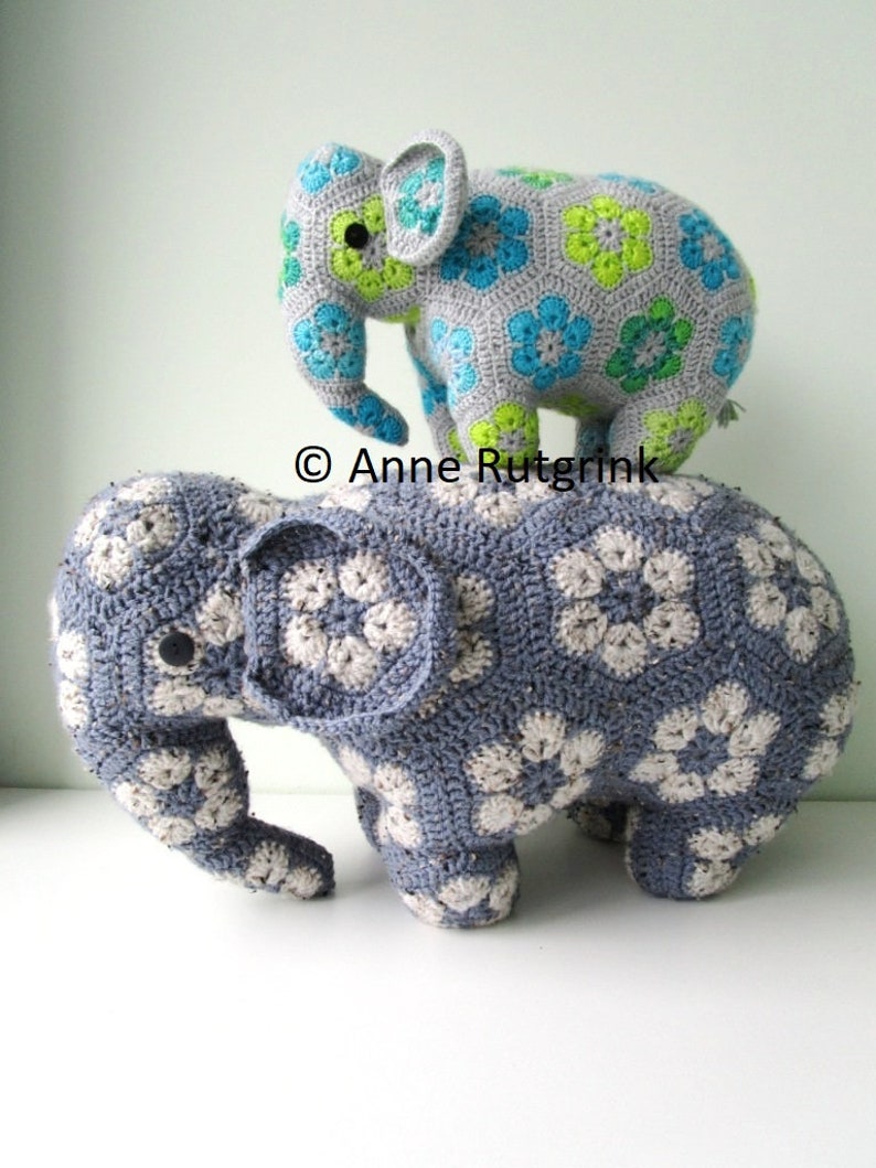 Op de afbeelding: Twee handgemaakte gehaakte olifantenspeeltjes. De grotere olifant is blauw met witte bloempatronen. De kleinere olifant is grijs met blauwe en groene bloempatronen. De speeltjes zijn zacht en knuffelig, perfect voor een kinderkamer.