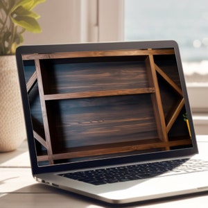 May include: A silver laptop computer with a wooden shelf displayed on the screen. The laptop is open and sitting on a light wood table next to a white coffee cup and saucer.