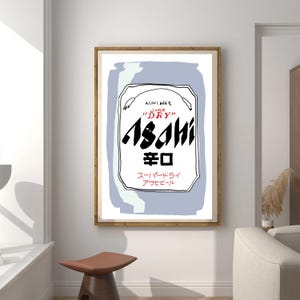 Puede incluir: Un cuadro enmarcado con una ilustración estilizada de una lata de cerveza Asahi. El diseño incluye el nombre de la marca en negrita negra, caracteres japoneses y las palabras "Super Dry". El fondo es de color azul claro.