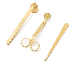 Op de afbeelding: Een set van drie gouden kaarsgereedschappen. De gereedschappen omvatten een kaarsdover, een paar kaarsdochtknippers en een kaarsdochtdipper.
