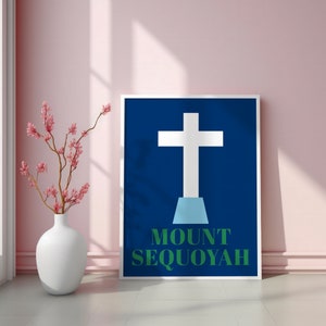 Op de afbeelding: Een wit kruis met een blauwe basis op een donkerblauwe achtergrond. De tekst "MOUNT SEQUOYAH" staat in het groen onder het kruis.