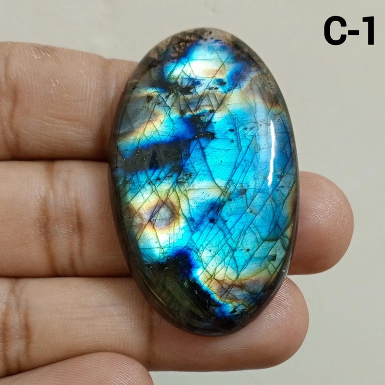 Peut inclure: Une pierre pr&eacute;cieuse de labradorite de forme ovale avec une surface polie. La pierre pr&eacute;sente un jeu de couleurs vibrant, avec des reflets bleus, verts et jaunes. La pierre pr&eacute;cieuse est &eacute;tiquet&eacute;e "C-1".