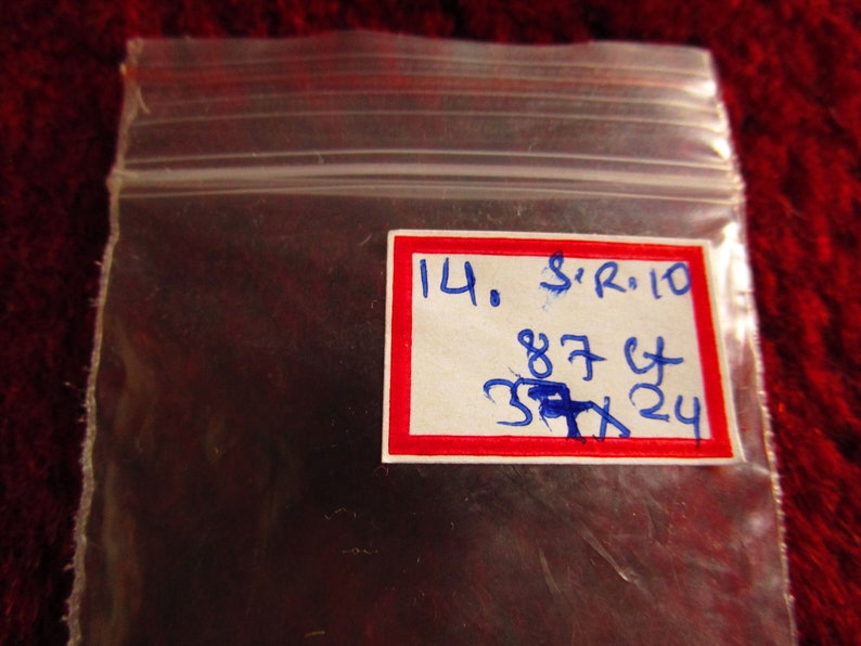 Puede incluir: Una etiqueta blanca con borde rojo y escritura azul. La etiqueta dice "14. S'R. 10 87 Ct 37x24".