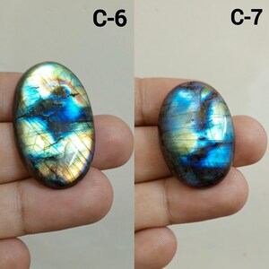 Peut inclure: Deux pierres pr&eacute;cieuses ovales en labradorite. La pierre de gauche, &eacute;tiquet&eacute;e "C-6", pr&eacute;sente une irisation bleue, verte et dor&eacute;e. La pierre de droite, &eacute;tiquet&eacute;e "C-7", est principalement bleue et verte avec un effet iris&eacute; similaire.