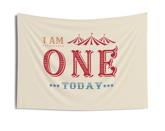 Pode incluir: Uma faixa bege com o texto "I am one today" em letras vermelhas e azuis. O número um está em uma fonte grande e estilizada. Há três tendas de circo vermelhas e brancas listradas acima do número um.