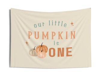 May include: A beige banner with the text "our little pumpkin is one" in orange and teal. Three watercolor pumpkins are in the bottom right corner.