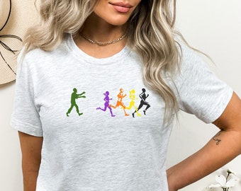 May include: A heather grey t-shirt with a graphic of a zombie chasing five runners. The runners are different colors: purple, orange, yellow, and black.