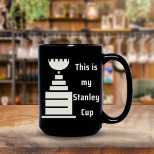 Pu&ograve; includere: Tazza da caff&egrave; nera con una grafica bianca del trofeo della Stanley Cup e il testo "This is my Stanley Cup".