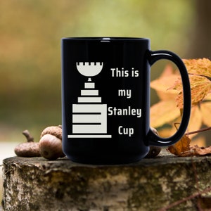 Pu&ograve; includere: Tazza da caff&egrave; nera con una grafica bianca del trofeo della Stanley Cup e il testo "This is my Stanley Cup".