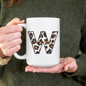 May include: White ceramic mug with a large letter W printed on the front. The letter is filled with a leopard print pattern in brown, black, and white.