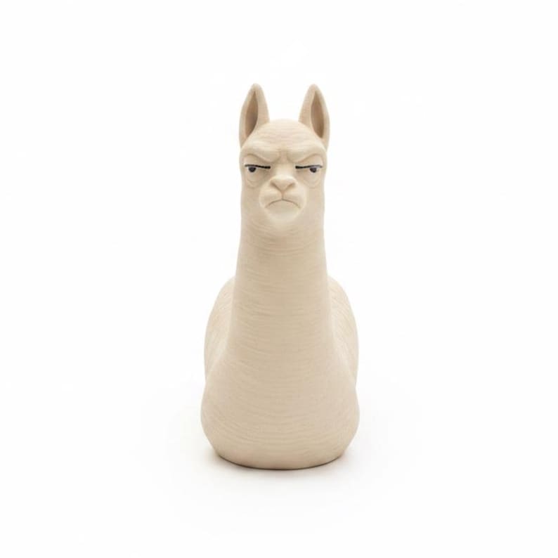 Puede incluir: Una figura de cer&aacute;mica beige con forma de alpaca, cuello largo y orejas puntiagudas. La alpaca tiene una expresi&oacute;n facial neutra con ojos oscuros y estrechos y una boca peque&ntilde;a, con una superficie texturizada que imita el pelaje.