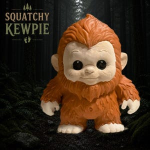 Puede incluir: Una figura de una criatura con pelaje marrón y cara, orejas, manos y pies de color claro. La figura tiene grandes ojos negros y una nariz pequeña. El texto SQUATCHY KEWPIE está impreso en la esquina superior izquierda sobre un icono de huella.