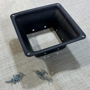 May include: A black, square speaker cabinet with a rectangular opening. The cabinet has several small holes for screws and is accompanied by a set of silver screws. The speaker cabinet is designed to house a speaker and is made of metal.