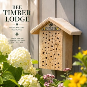 May include: A rectangular cedar bee house with a peaked roof and numerous circular nesting holes on the front face. A small sign at the top displays the text BEE TIMBER LODGE with a bee icon and yellow flower graphics on either side.