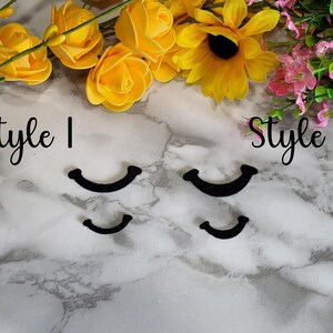 Può includere: Due stili di arricciacapiglia neri su una superficie di marmo bianco. Il testo "Style 1" e "Style 2" è scritto sopra gli arricciacapiglia.