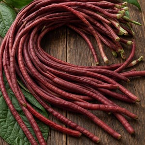 May include: A bundle of fresh, red yard-long beans, also known as Chinese long beans, arranged on a rustic wooden surface. The beans are a deep burgundy color, with green leaves in the background. The beans are a popular ingredient in Asian cuisine.