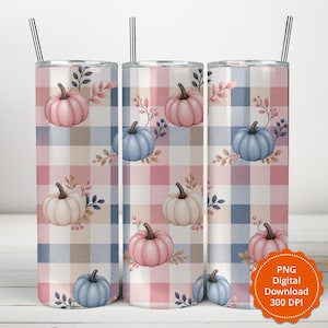 May include: A cylindrical tumbler featuring a plaid pattern in shades of pink, blue, and white, decorated with illustrations of pumpkins in pink, blue, and cream colors, accented with small leaves and berries, and topped with a thin black straw.