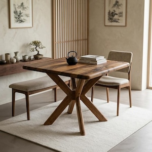 Peut inclure: Une table à manger carrée en bois avec un grain brun foncé et une base en croix. La table est accompagnée d'un long banc et d'une chaise, tous deux dotés de sièges rembourrés beige clair et de cadres en bois, formant un ensemble cohérent.