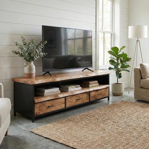 Puede incluir: Un mueble de televisi&oacute;n rectangular con una superficie de madera natural de borde vivo y una estructura de metal negro. La unidad incluye un estante de almacenamiento abierto y tres cajones inferiores con herrajes de metal oscuro.