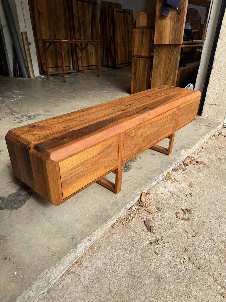 Finished walnut TV stand in workshop showcase before shipping