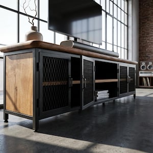 Peut inclure: Un meuble TV moderne avec un dessus et des portes en bois, et un cadre en métal noir. Les portes ont un motif en treillis en losange. Une barre de son et une télévision sont posées sur le dessus. La pièce a de grandes fenêtres et un mur de briques.