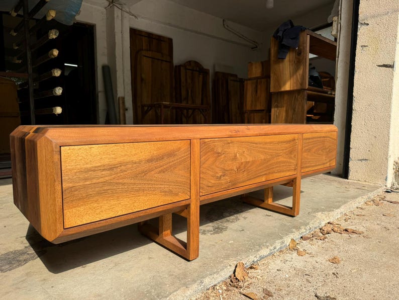 Modern walnut TV stand in handcrafted workshop lighting