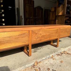 Handcrafted walnut TV unit standing on wooden legs, symbol of natural beauty and precision